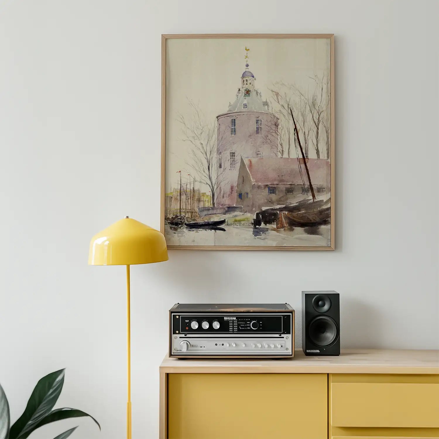 Framed painting of a waterway scene with a building and boats, displayed above a mid-century modern yellow lamp and a stereo system on a wooden cabinet.