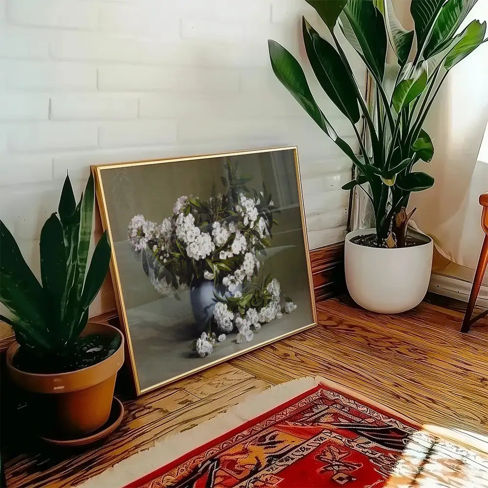 Framed painting of a bouquet of white flowers in a blue vase, positioned beside indoor plants in a cozy living space.