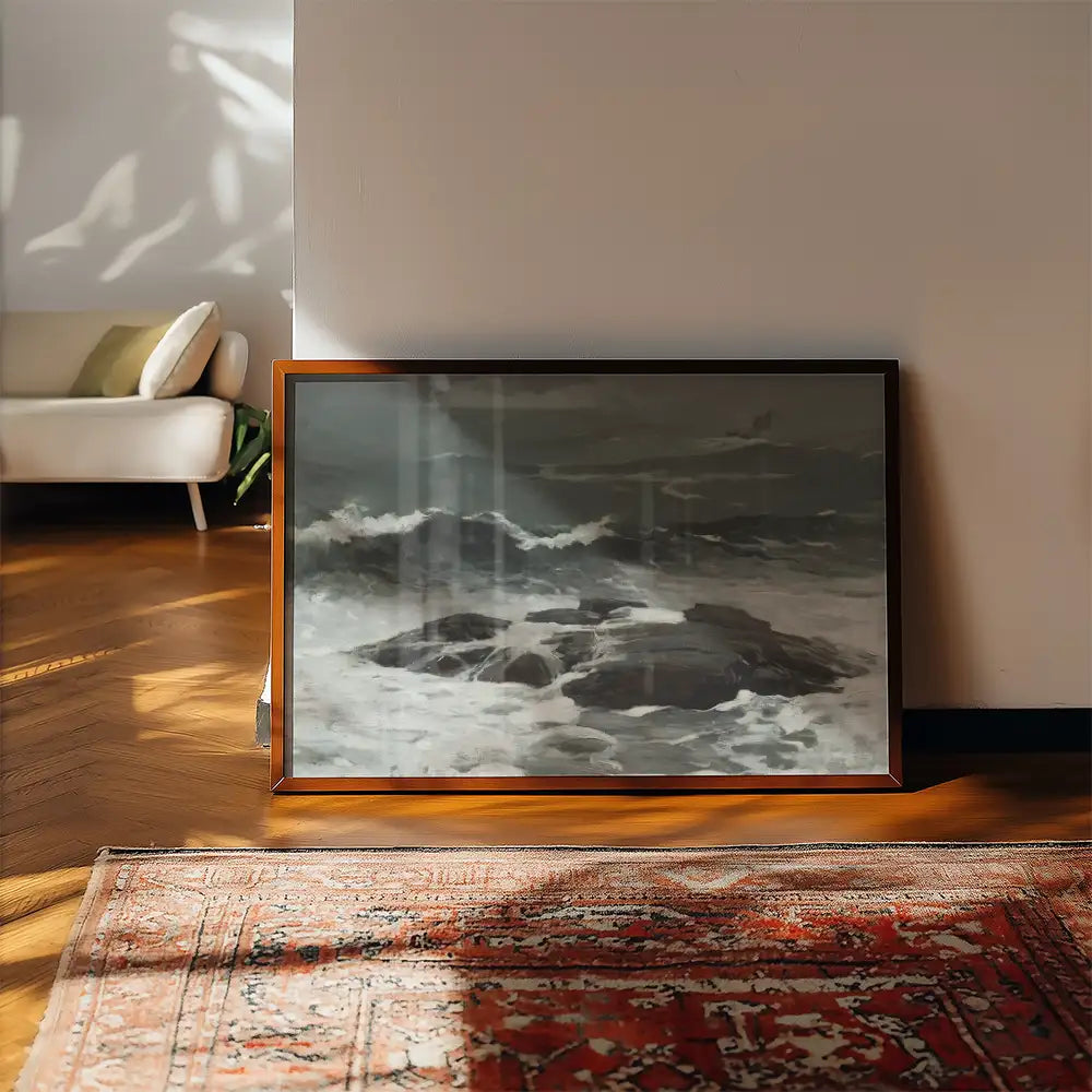 Framed artwork depicting turbulent ocean waves crashing against rocks, placed on a wooden floor in a stylish interior setting.