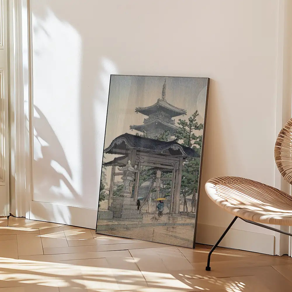 Framed painting of a traditional Japanese pagoda among trees, leaning against a wall in a modern interior setting.