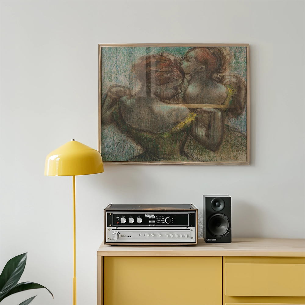 Painting of two women in a tender embrace, framed and displayed on a wall above a yellow floor lamp and a stereo system on a modern wooden cabinet.