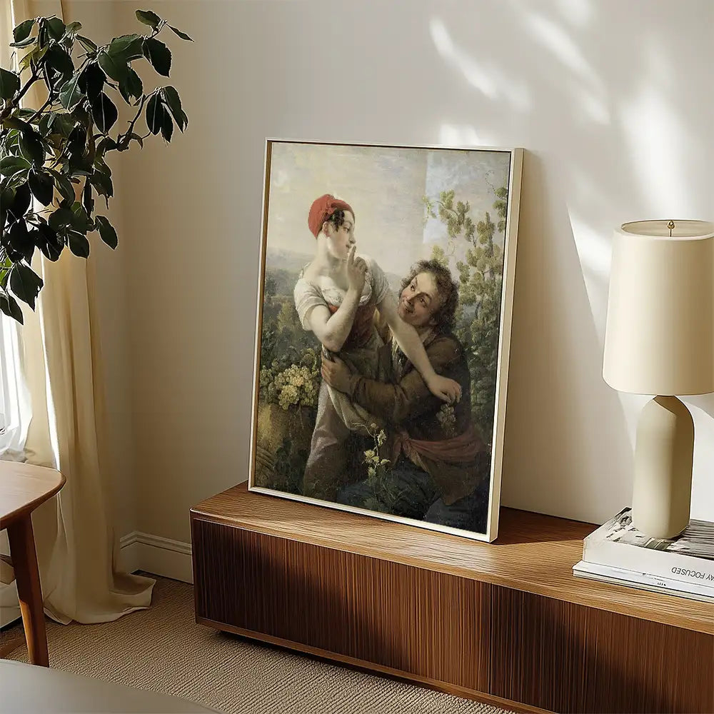 Painting of a woman and a man surrounded by greenery, displayed in a modern living room setting with a wooden console and a lamp.