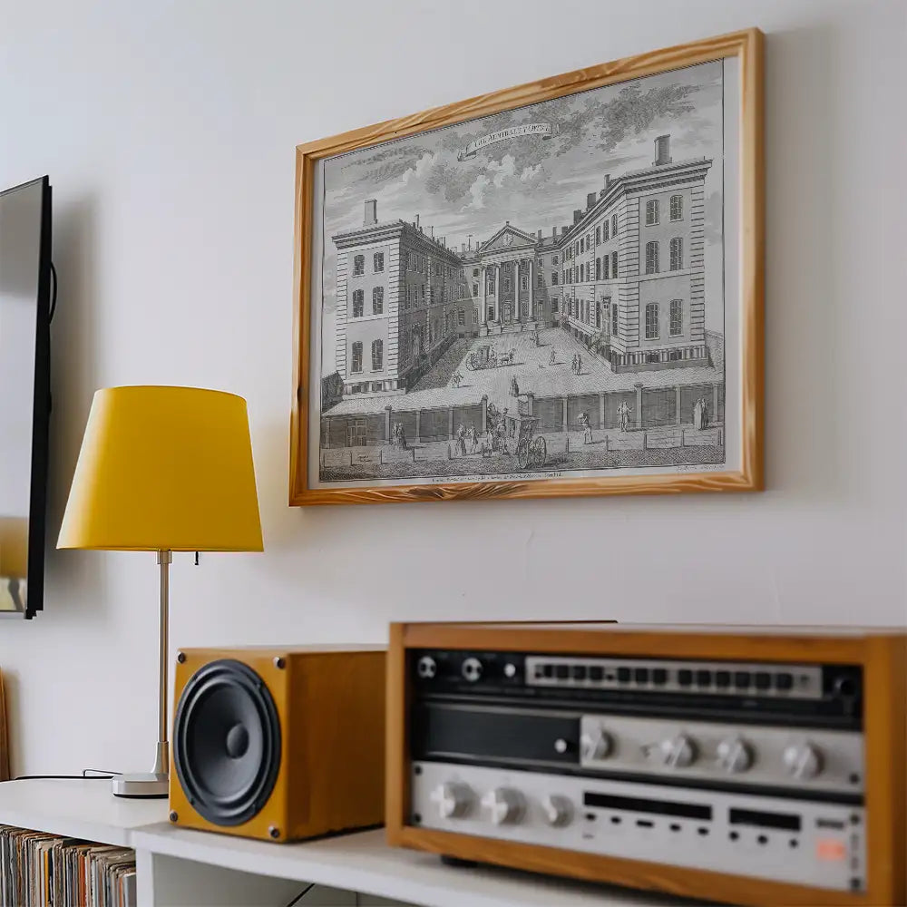 Framed black and white architectural print hanging on a wall above a yellow lamp and vintage audio equipment.
