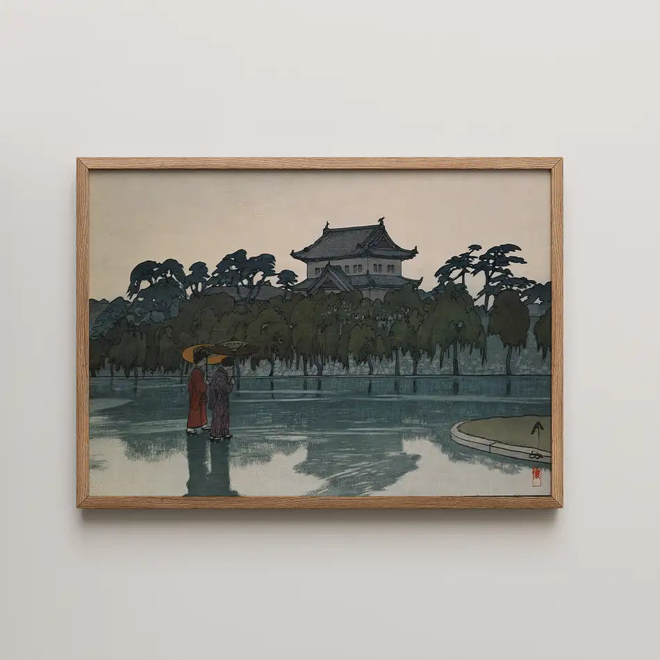 Framed painting depicting two figures with umbrellas by a serene body of water and a traditional building in the background.