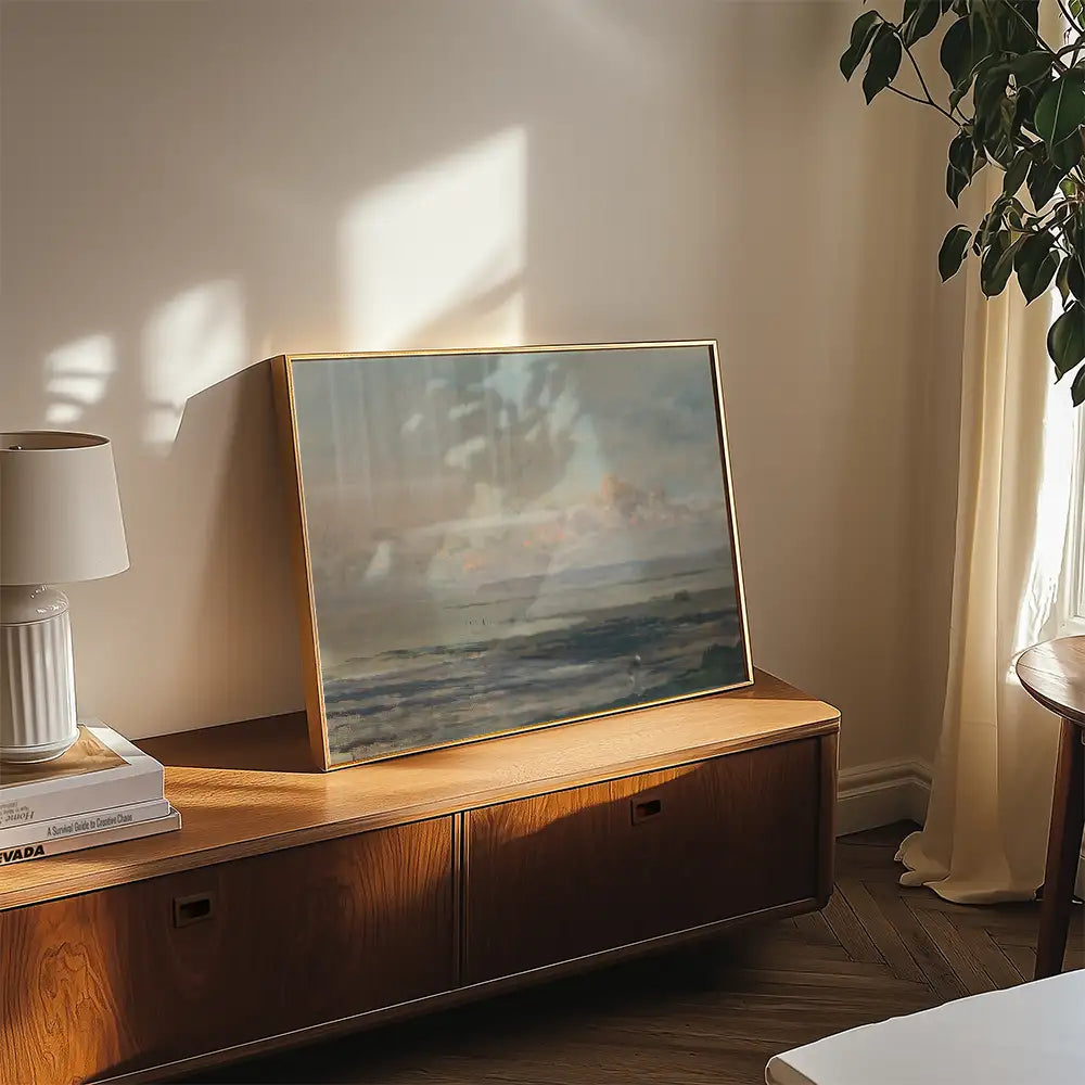 Framed painting of a serene seascape displayed on a wooden console table in a well-lit room.