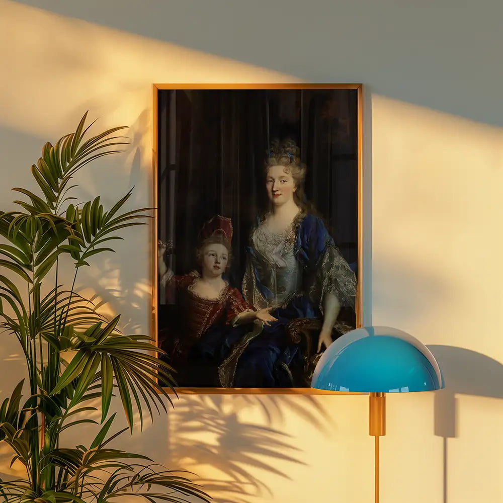 Portrait of two regal figures, a woman in a blue gown and a child in red, framed in a modern wooden frame, displayed on a wall with a lamp and plant in the foreground.