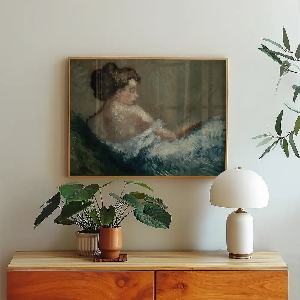 Painting of a woman reclining with soft brush strokes, framed and displayed above a wooden console table adorned with a potted plant and a table lamp.