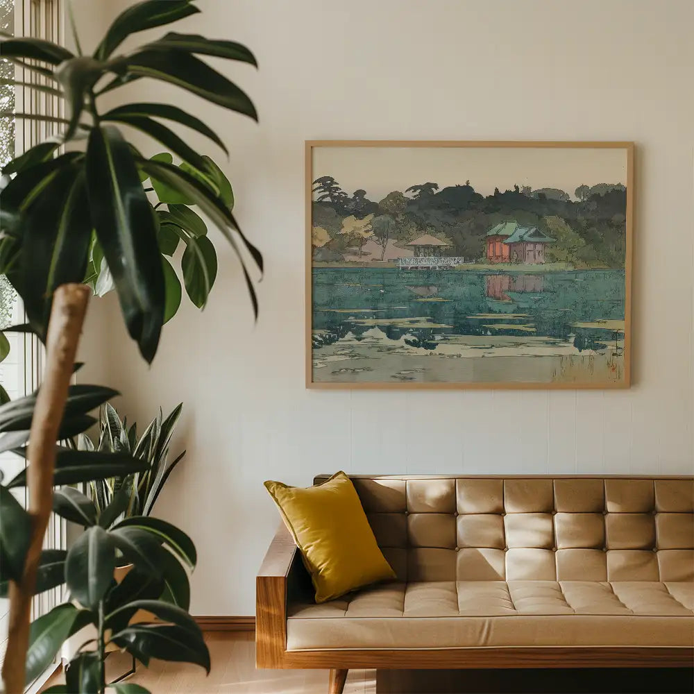 Framed painting of a tranquil lake scene with reflections, displayed on a white wall above a mid-century modern sofa with a yellow cushion, surrounded by indoor plants.