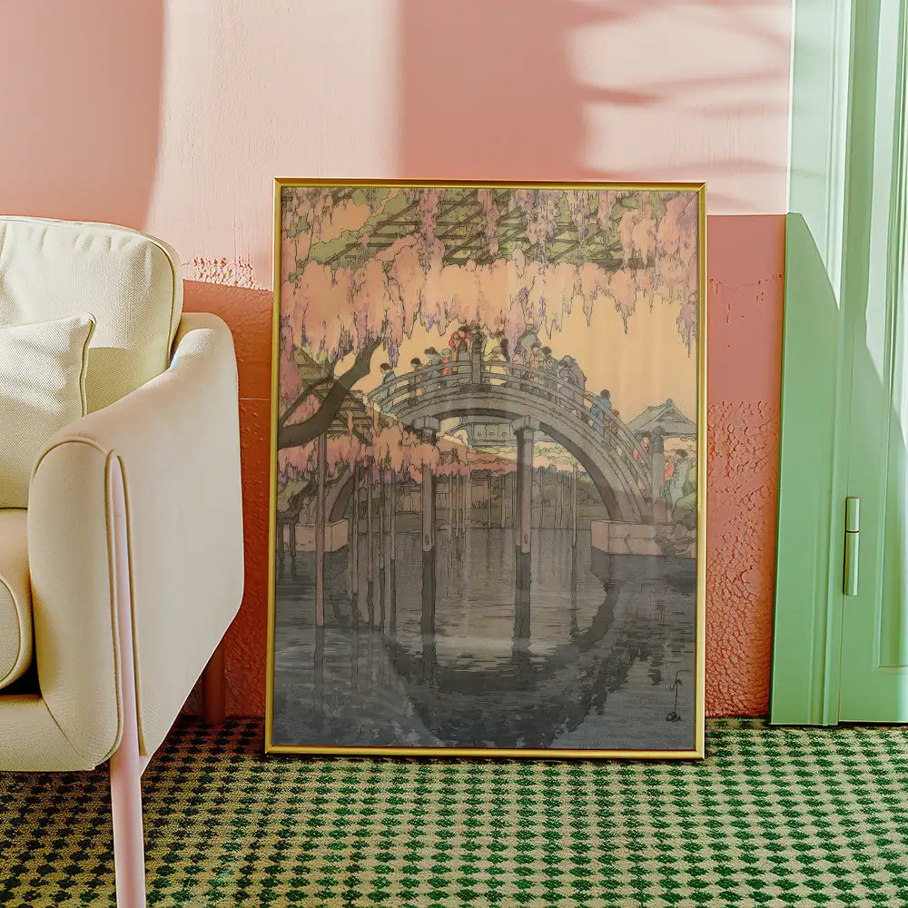 Framed painting of a serene bridge surrounded by cherry blossom trees, set against a pastel pink wall and green door, with a cozy chair nearby.