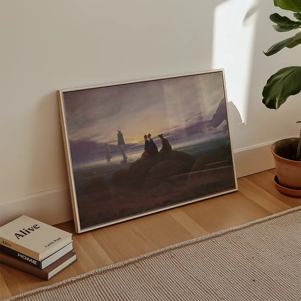 Framed painting of two figures and a dog sitting on rocks by the sea with boats and a lighthouse in the background, placed against a wall in a cozy room.