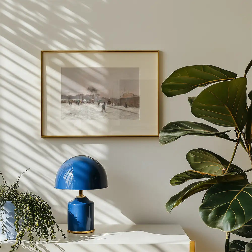 Framed painting of a winter scene with people holding umbrellas, displayed on a wall with a blue table lamp and a green plant nearby.