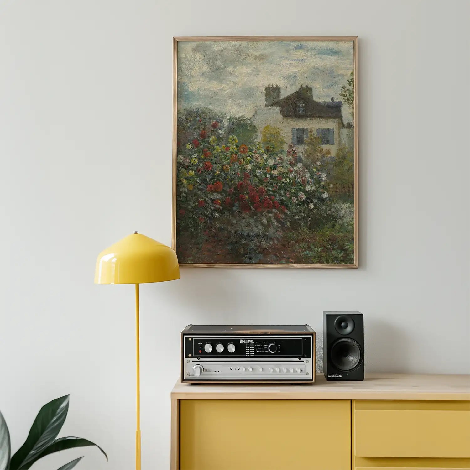 A vibrant floral painting in a light wooden frame hanging on a white wall above a yellow lamp, a vintage audio receiver, and a black speaker on a wooden sideboard.