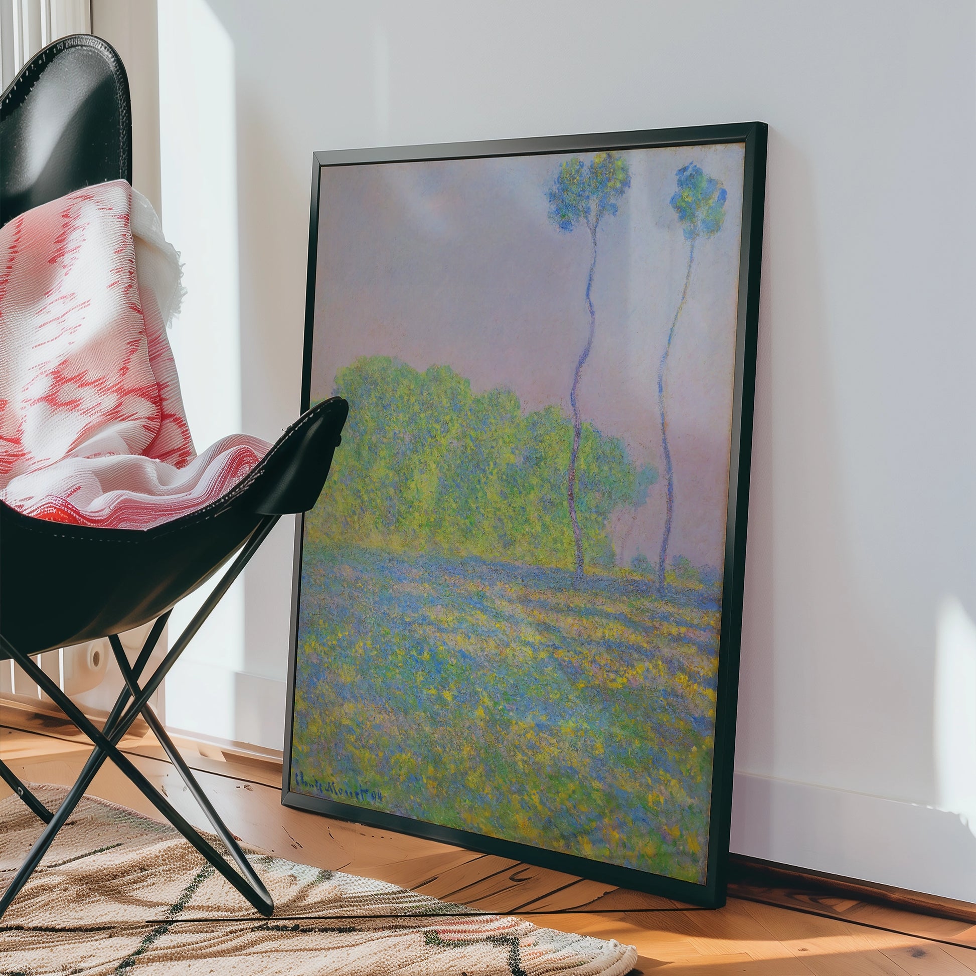 Framed painting of a serene landscape featuring green trees and a pastel sky, leaning against a wall beside a modern black chair and a patterned rug.
