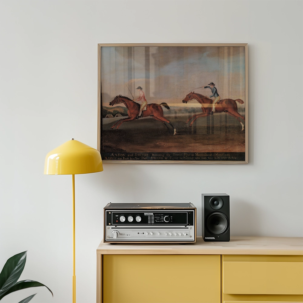 Painting of two horse riders in a race, framed and displayed on a wall above a yellow lamp and vintage audio equipment.