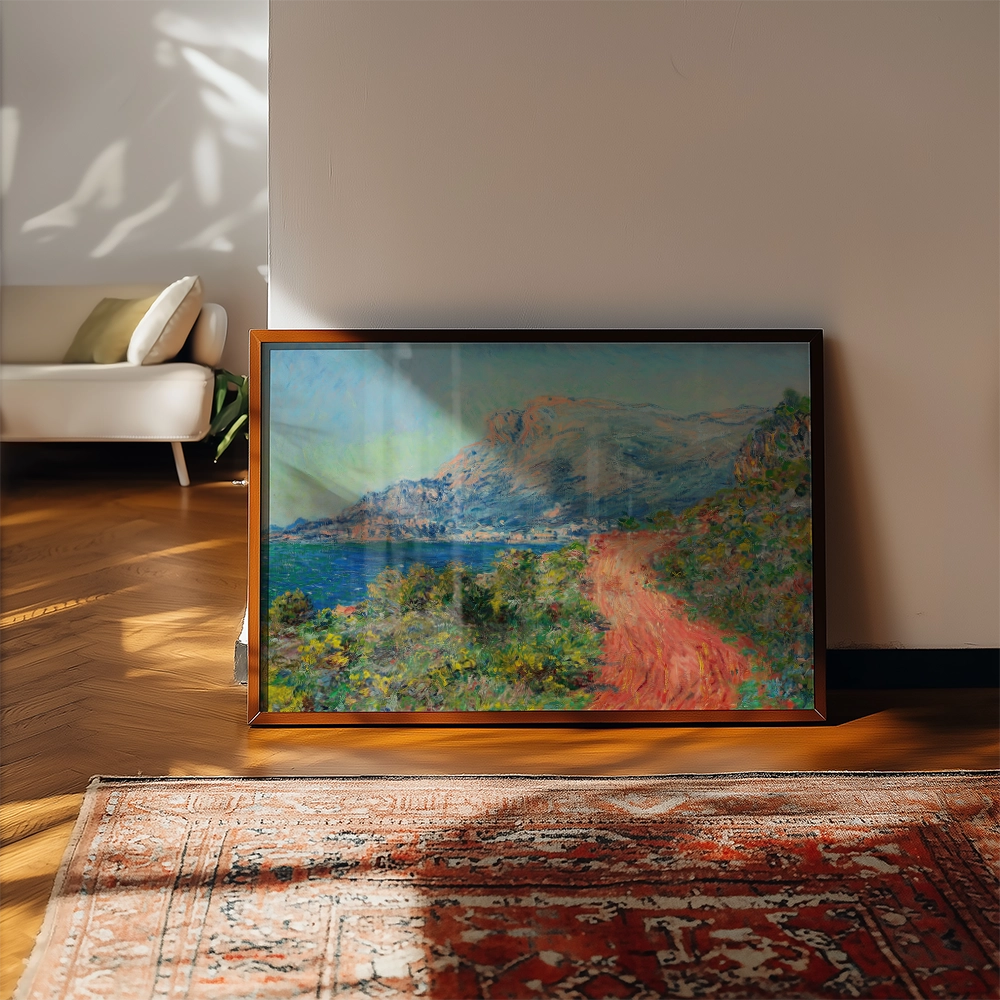 A vibrant landscape painting of a coastal scene featuring mountains, a winding path, and lush greenery, displayed in a wooden frame on a wooden floor with a patterned rug.