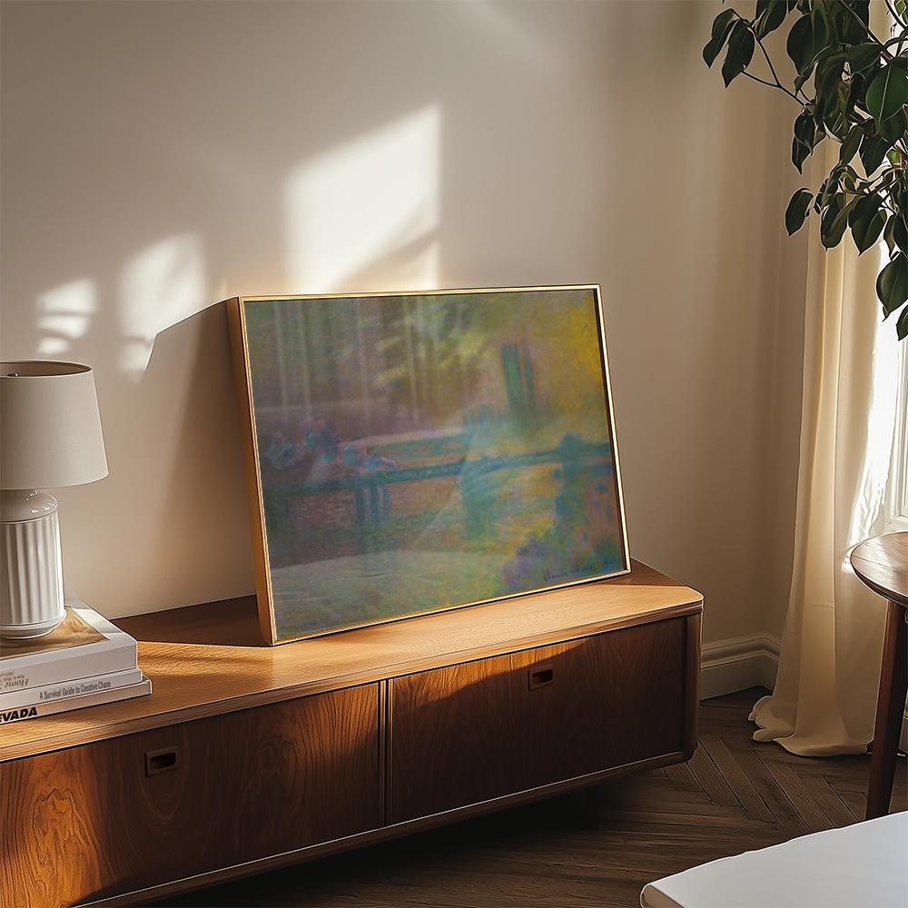 Framed painting resting on a wooden cabinet in a warmly lit room, with a lamp and plant in the background.
