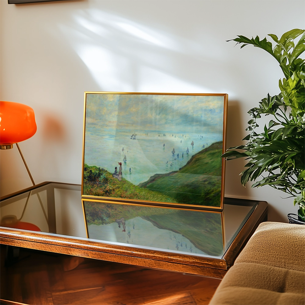 Painting of a serene beach scene displayed on a wooden table, with an orange lamp and a leafy plant in the background.