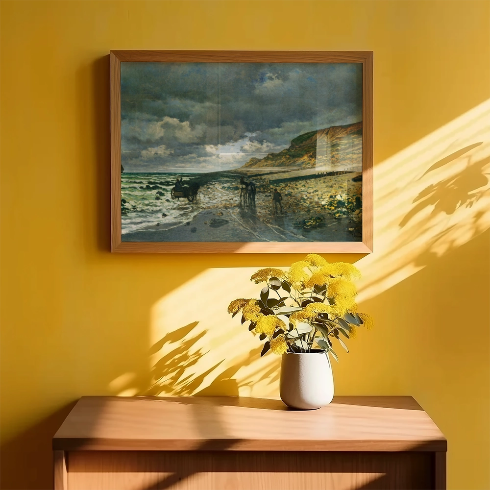 Framed painting of a coastal scene with horses on a beach, displayed on a yellow wall above a wooden table with a vase of yellow flowers.