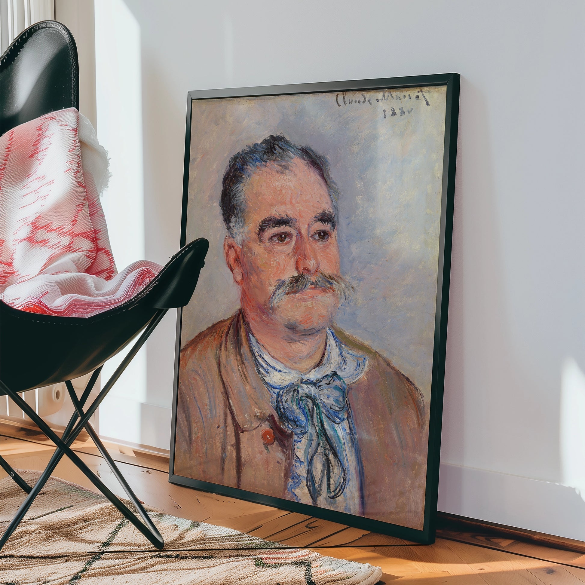 Portrait painting of a man with a mustache in a black frame, displayed in a modern interior setting with a chair and a woven rug.