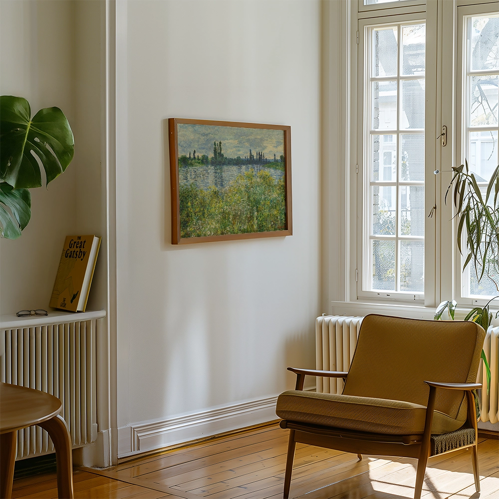 Interior view of a room featuring a framed painting of a landscape on the wall, with a brown chair and a plant near a window.