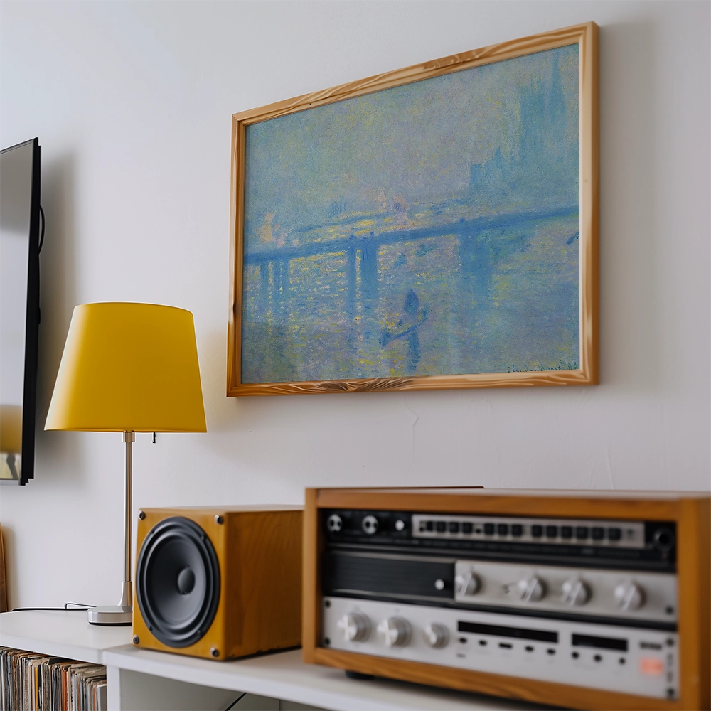 Painting with soft blue hues depicting a dock scene, framed in wood, displayed above a yellow lamp and vintage audio equipment.