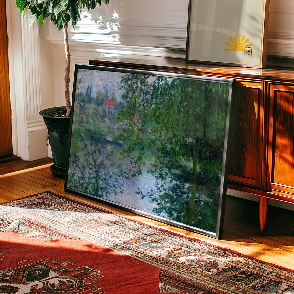 Framed painting leaning against a wooden cabinet, featuring a serene landscape with greenery and a body of water, illuminated by sunlight in a cozy interior setting.