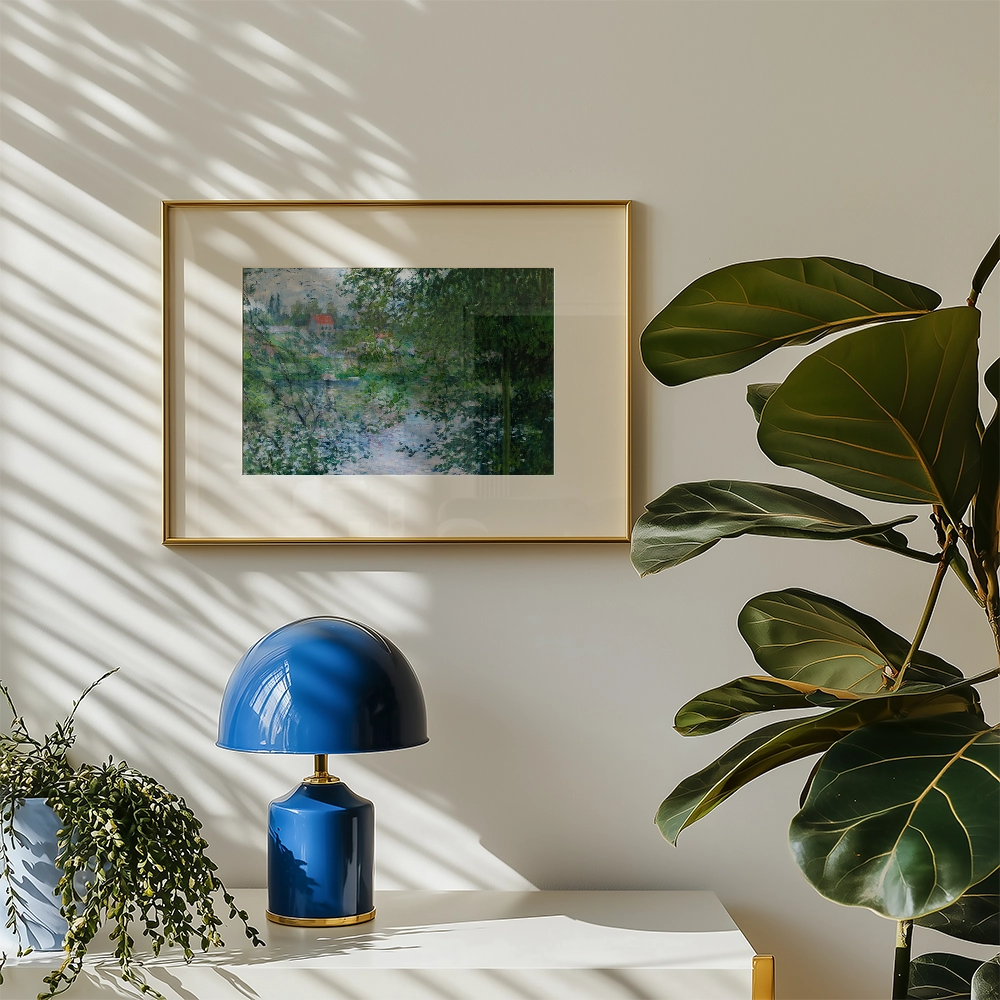 Framed landscape painting on a wall with a blue lamp and a green plant in a bright room.