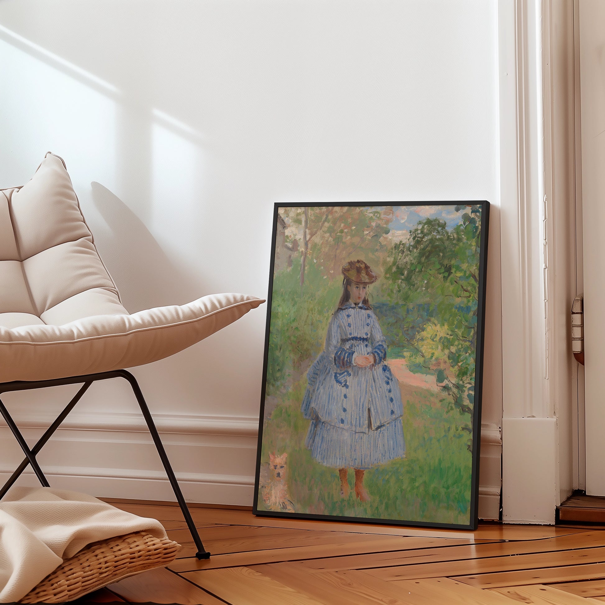 Painting of a girl in a blue striped dress standing in a garden, framed and leaning against a wall next to a modern chair.