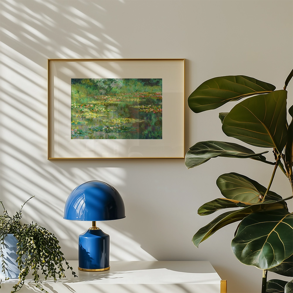 Framed painting of a serene water lily scene hanging on a wall, with a blue lamp and a lush green plant in the foreground.