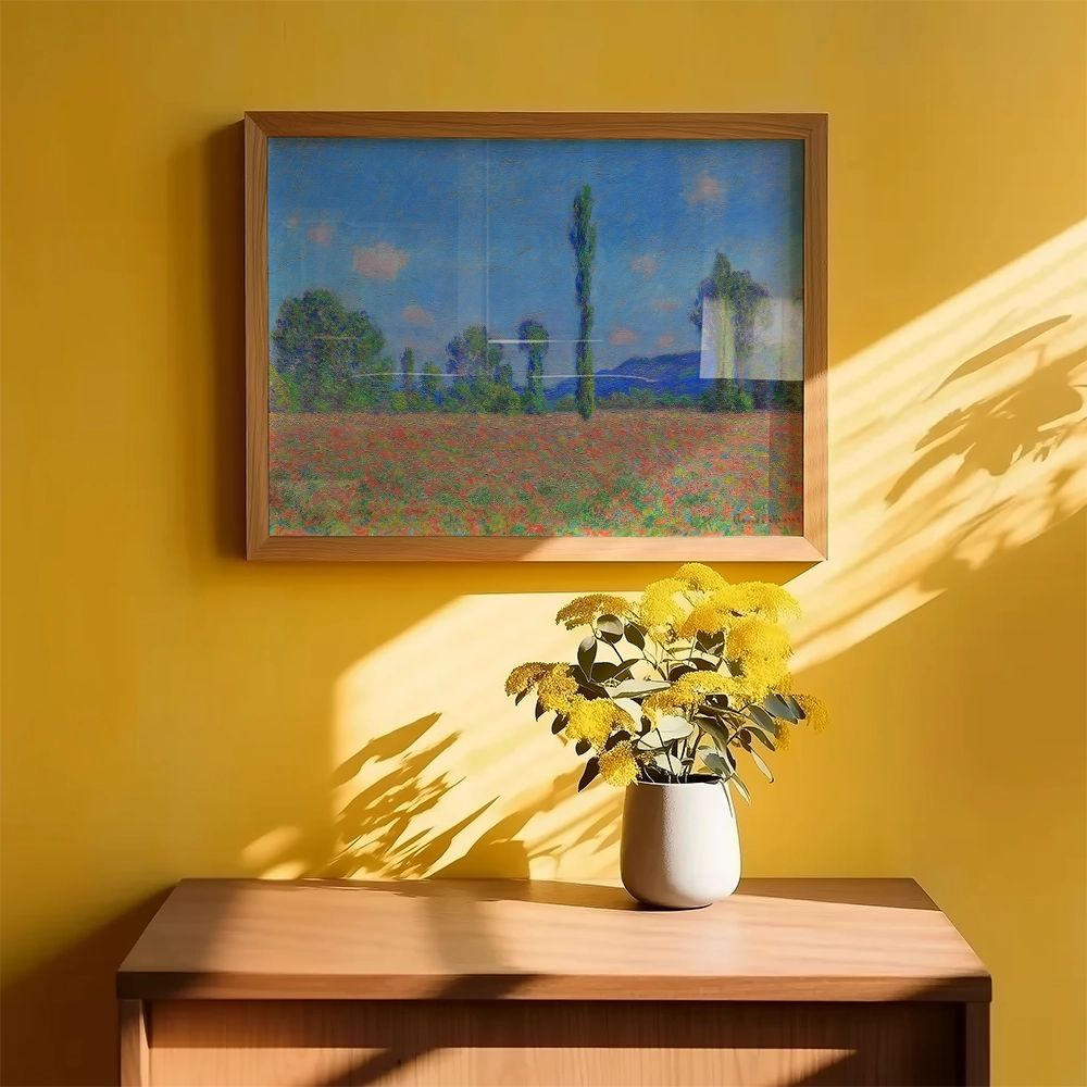 Painting of a vibrant landscape featuring a field with flowers, framed and hanging on a bright yellow wall, with a vase of yellow flowers on a wooden table below.