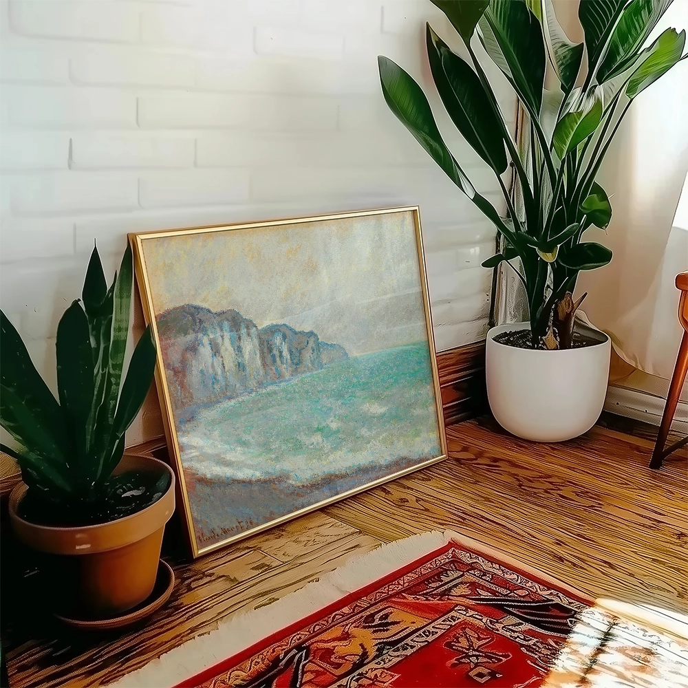Framed coastal painting featuring cliffs by the sea, placed against a bright interior with plants.