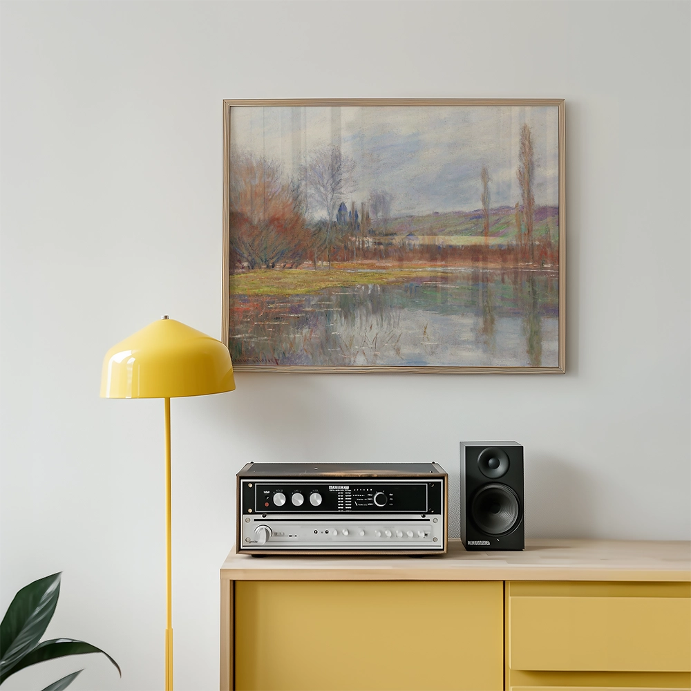 Painting of a serene landscape with a river and trees, framed and displayed on a wall above a yellow lamp and a stereo system on a wooden cabinet.