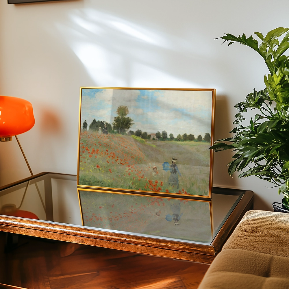 Painting of a serene landscape featuring a field of red poppies, with two figures in the background, displayed on a wooden table beside a potted plant and a modern orange lamp.