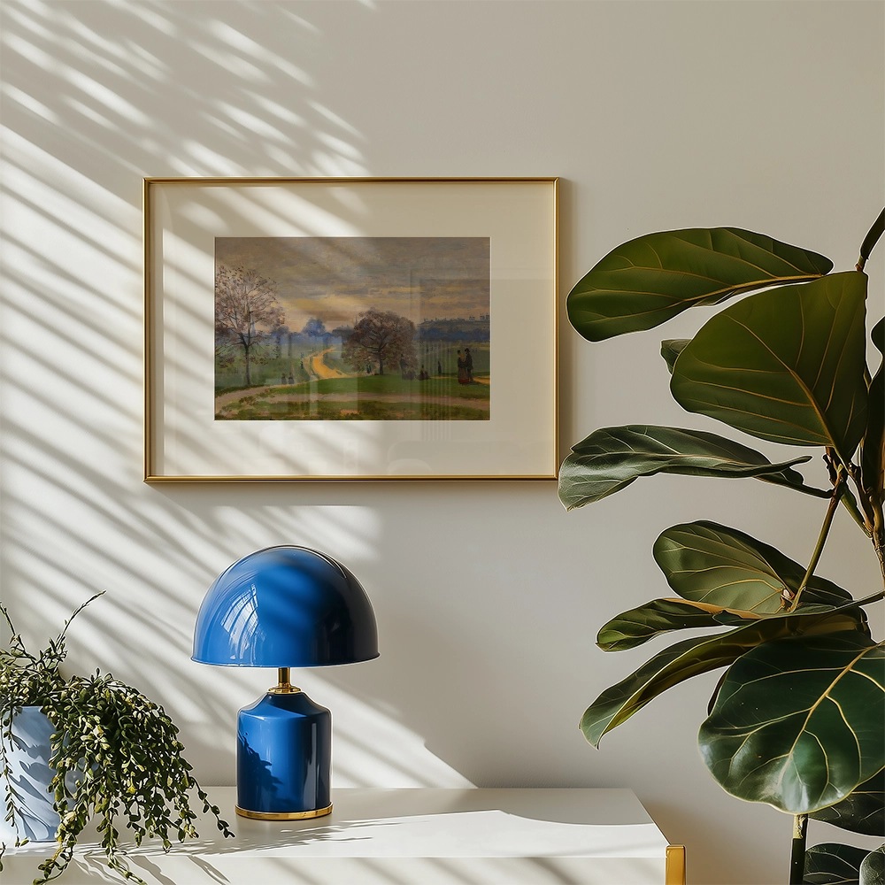 Framed painting of a serene landscape with trees and a winding path, displayed on a wall beside a blue lamp and a potted plant.
