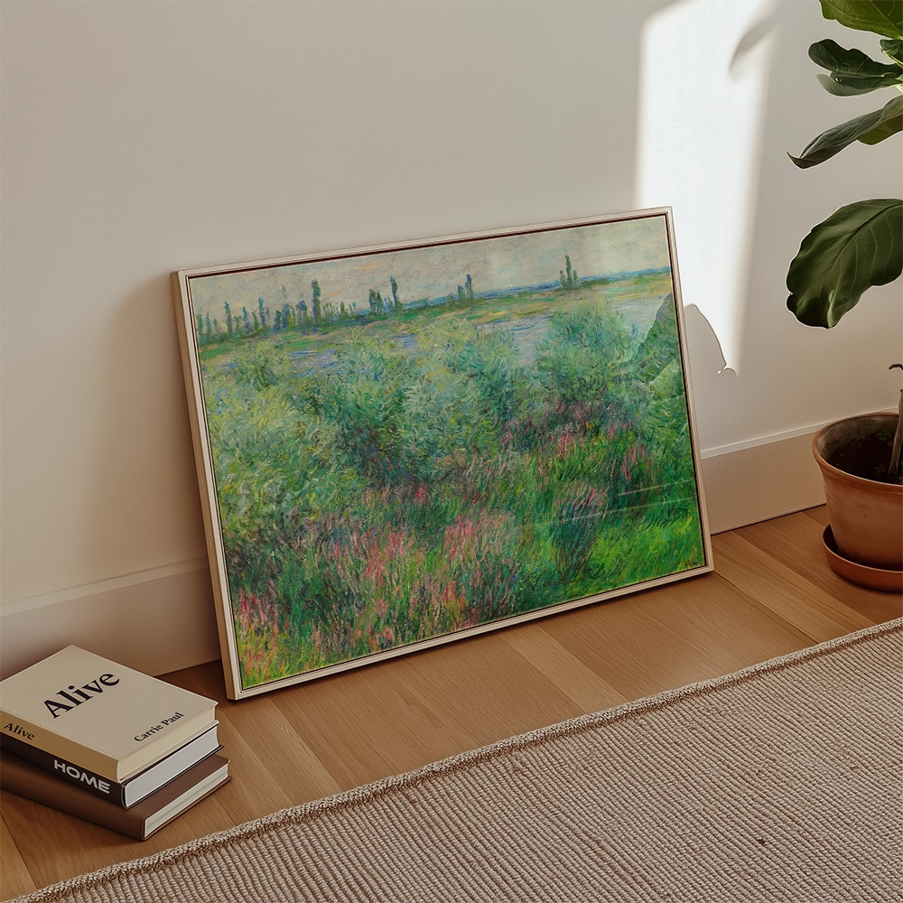 Framed painting of a vibrant landscape featuring green bushes and a serene body of water, placed against a light wall with decorative books nearby.