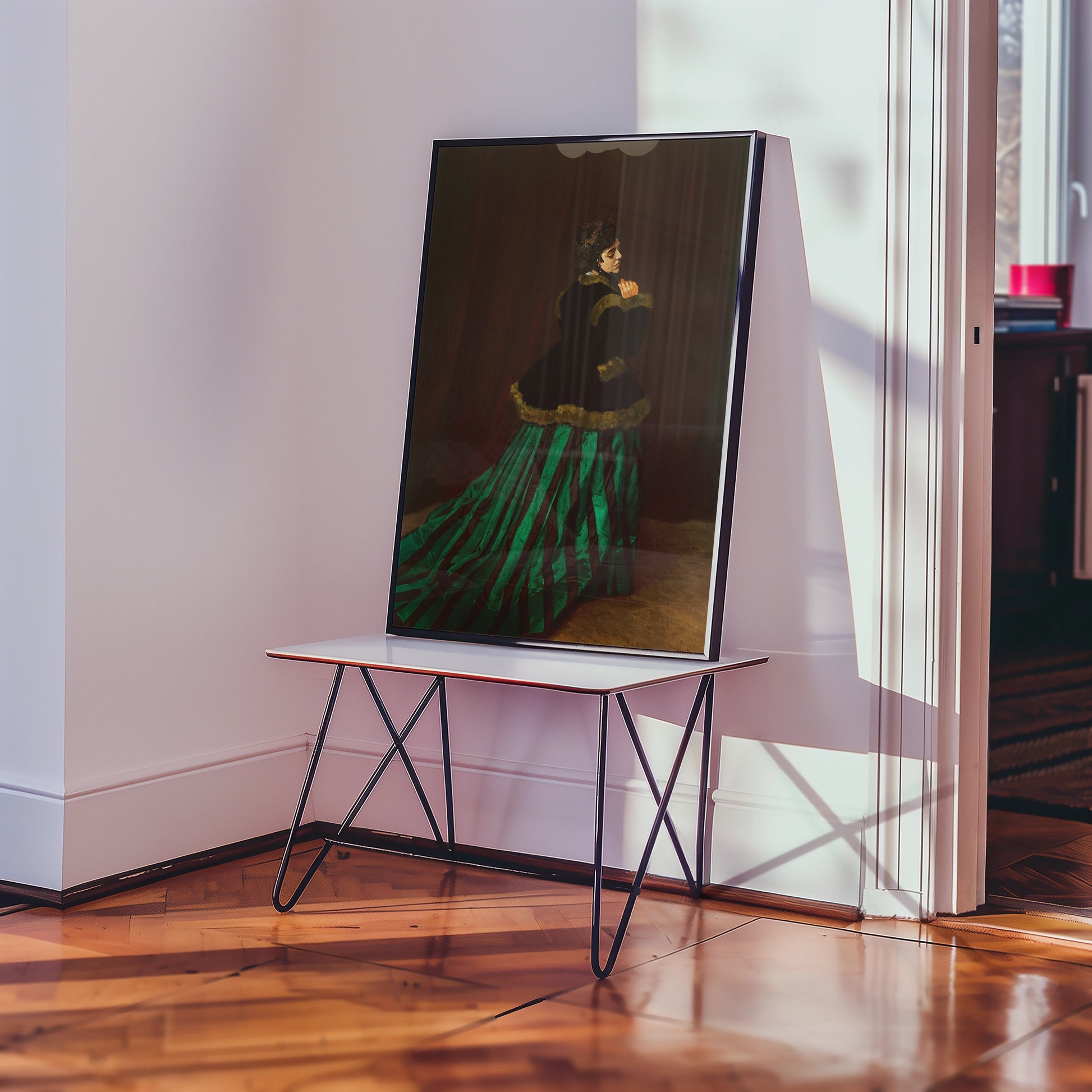 Framed painting of a woman in a dark dress with a striped skirt displayed on a white table in a bright room.