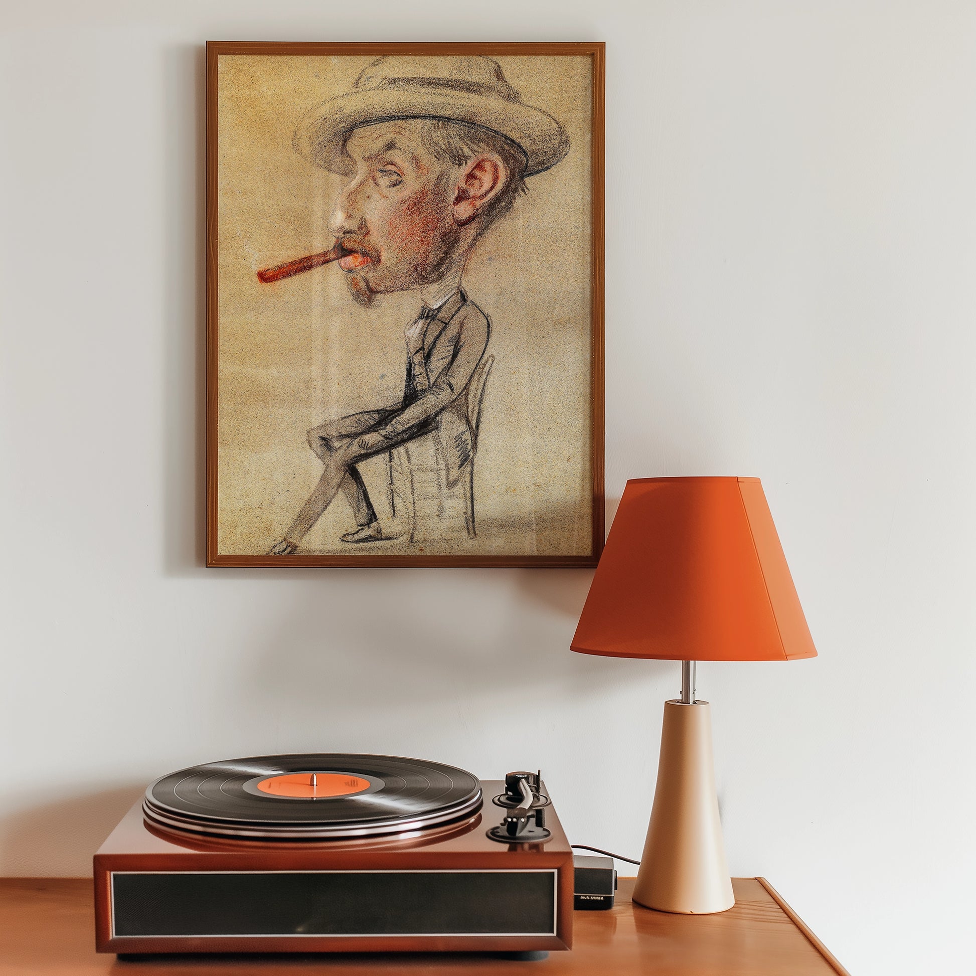 Caricature painting of a man with a pipe, framed and displayed on a wall beside a vintage record player and a modern orange lamp.