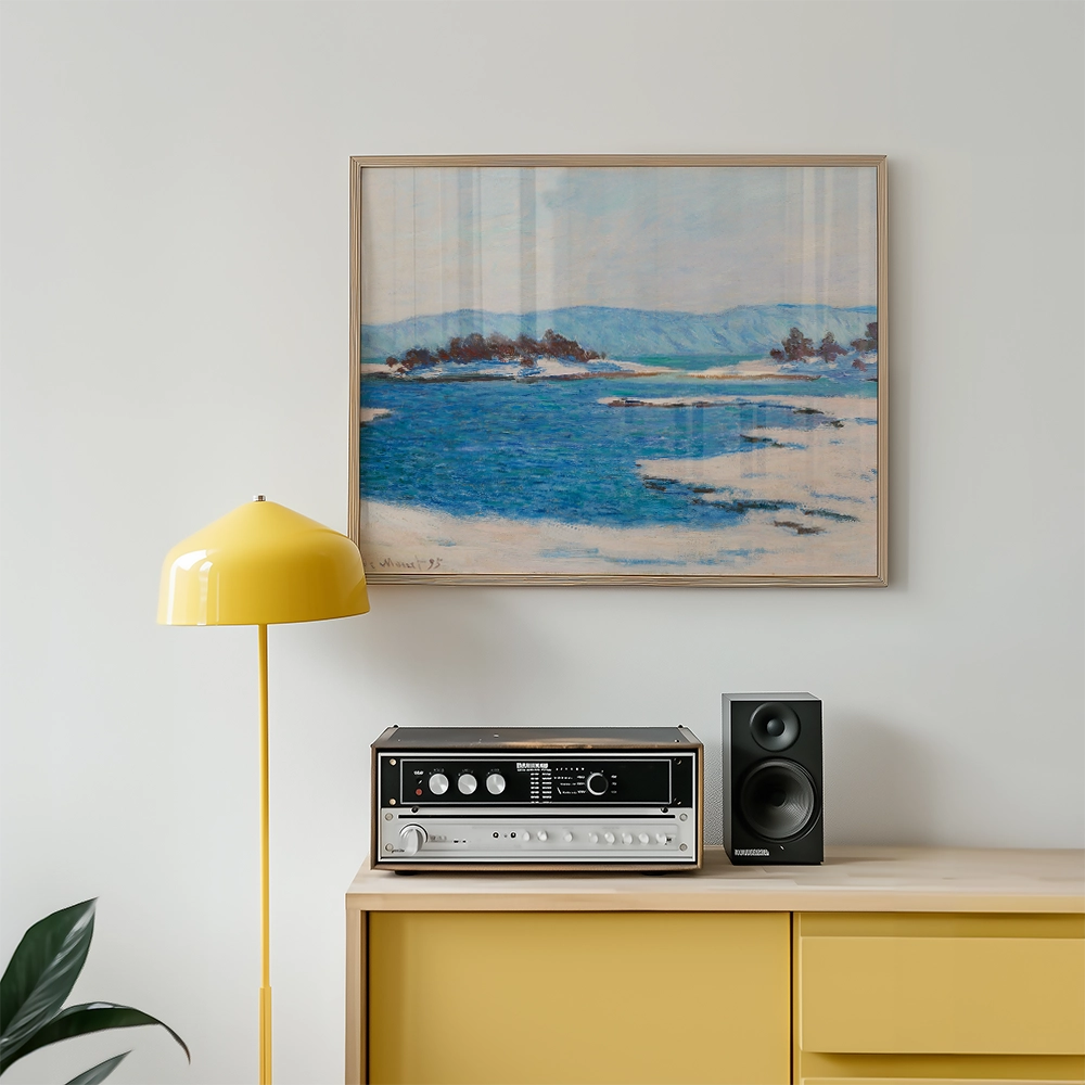 Painting of a serene blue ocean landscape framed and hung above a modern yellow lamp and audio equipment on a light wooden cabinet