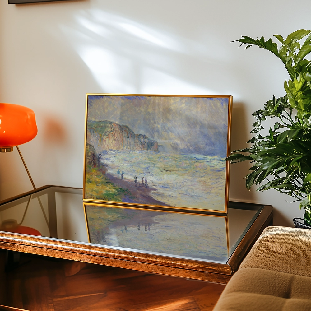 Painting of a seascape with people walking along the shore, displayed in a gold frame on a wooden table with a mirror surface and greenery nearby.