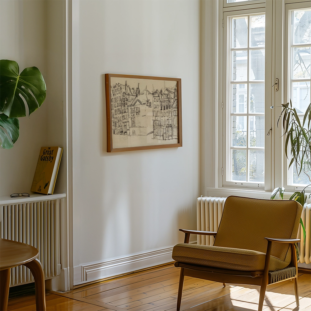 Framed drawing of buildings on a wall in a stylish living room with a beige chair and indoor plant.