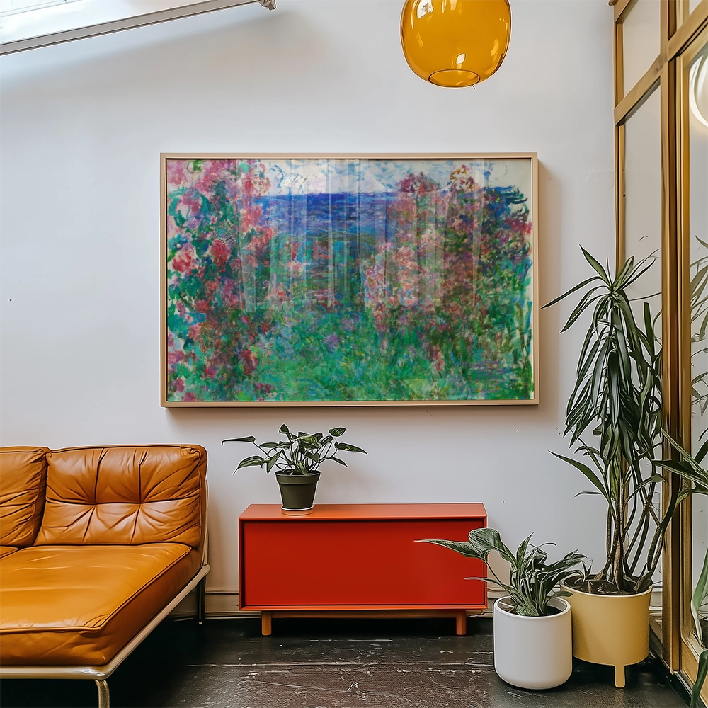 Framed painting of a colorful garden with flowers and greenery hanging on a wall above an orange sofa and a red cabinet in a modern interior setting.