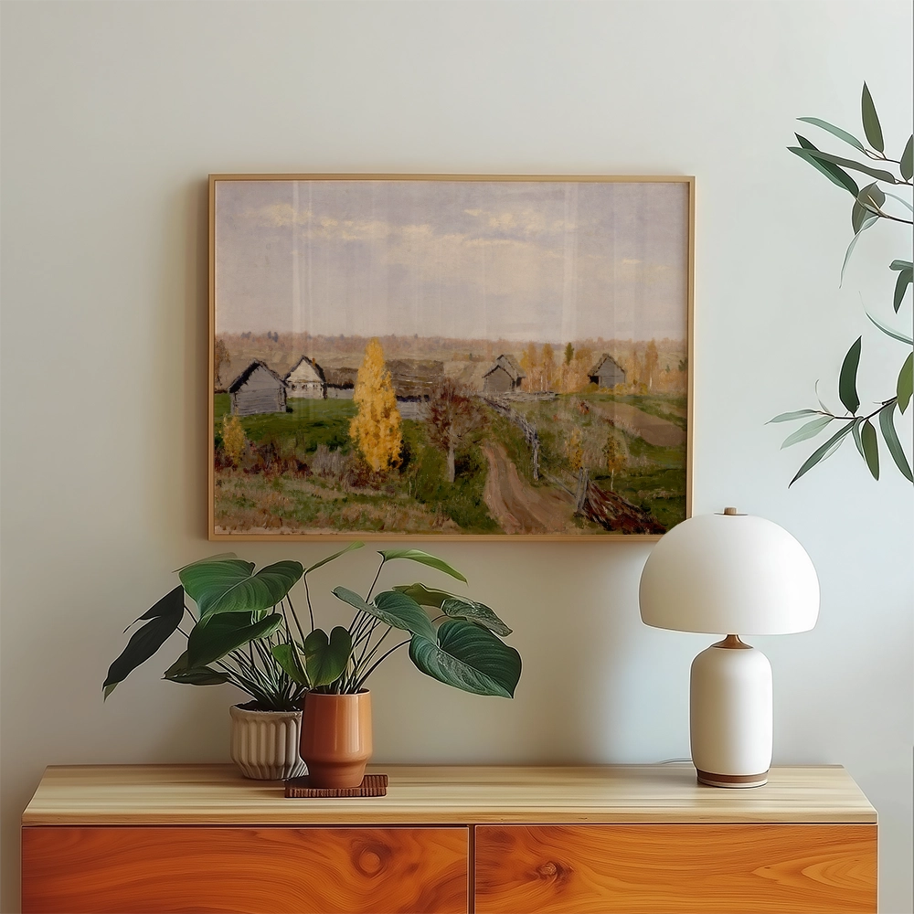 Painting of a serene landscape featuring rustic cottages and autumn trees, displayed above a wooden sideboard with a potted plant and a stylish lamp.