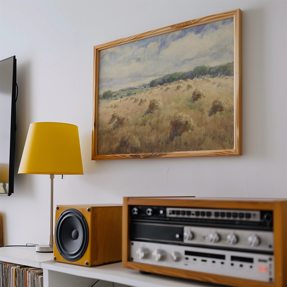 Framed painting of a serene landscape featuring fields and distant trees, displayed on a wall alongside a yellow lamp and a vintage audio system.