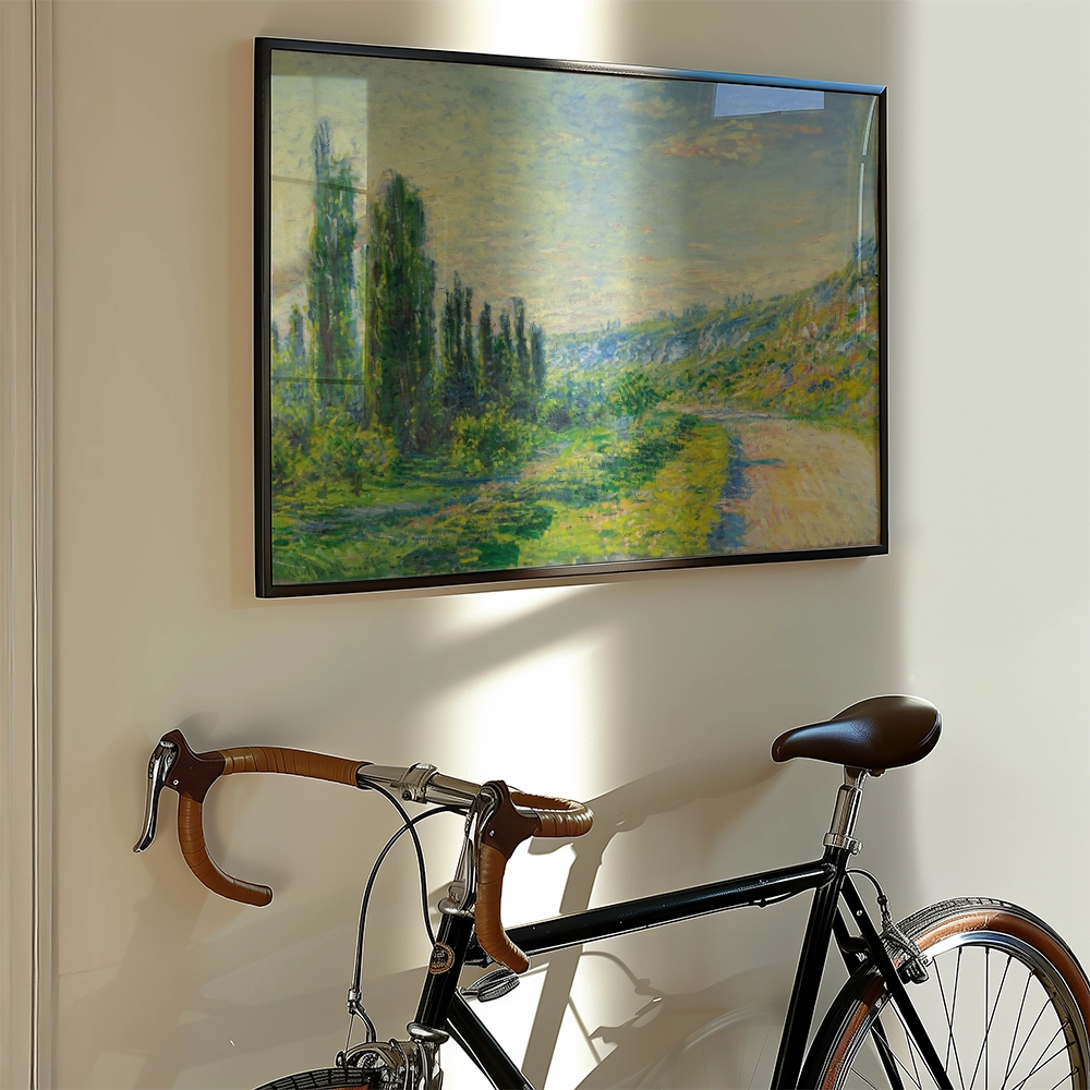 Painting of a landscape featuring trees and a winding path, framed and hung on a wall beside a black bicycle with brown handlebars.
