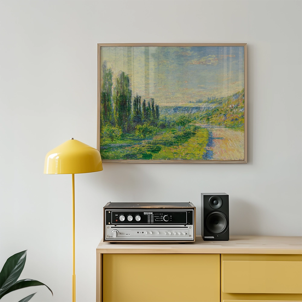 Framed painting of a scenic landscape with trees and a road, displayed above a yellow lamp and a vintage audio system in a modern interior setting.