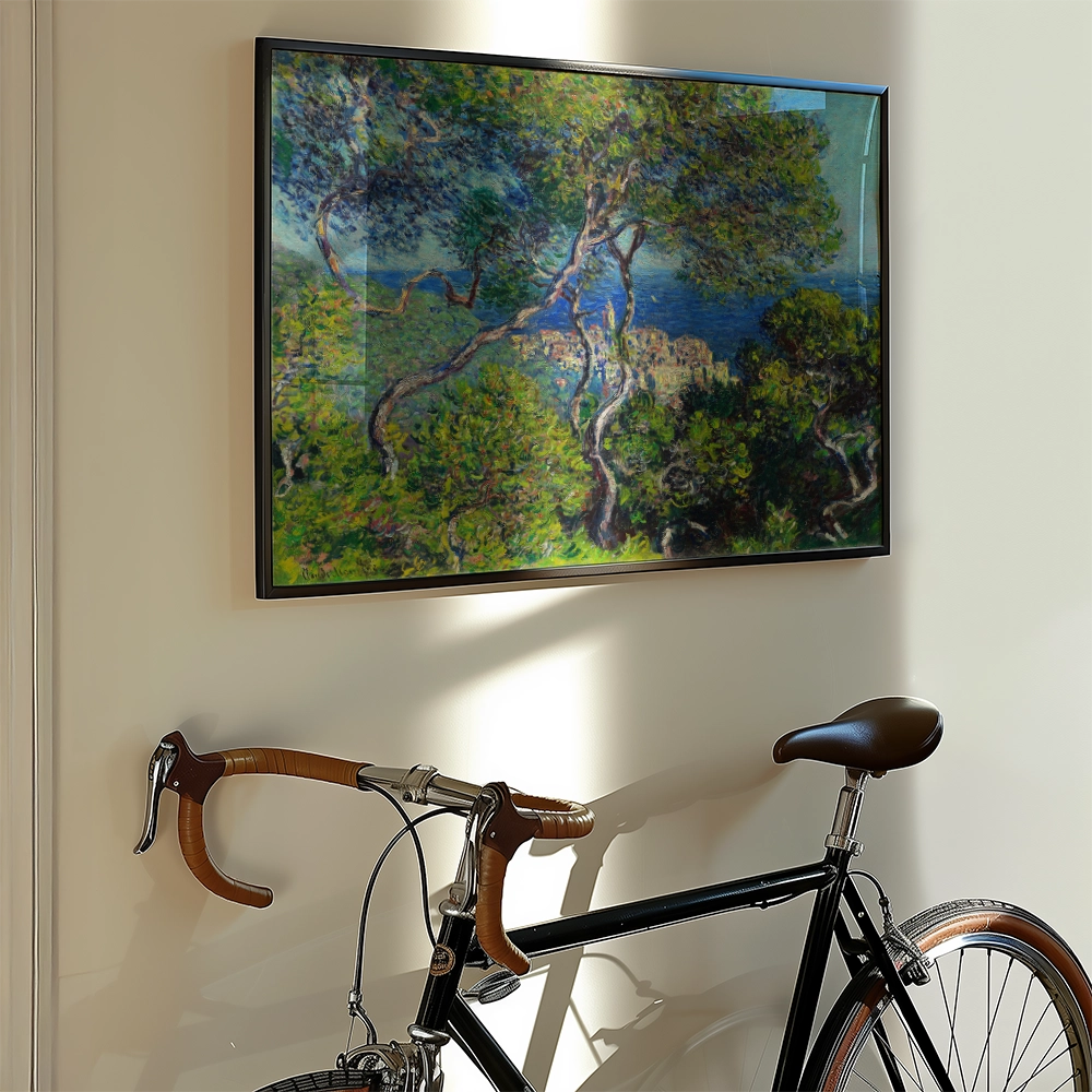 Framed painting of a lush landscape with trees and the sea displayed on a wall next to a vintage bicycle.