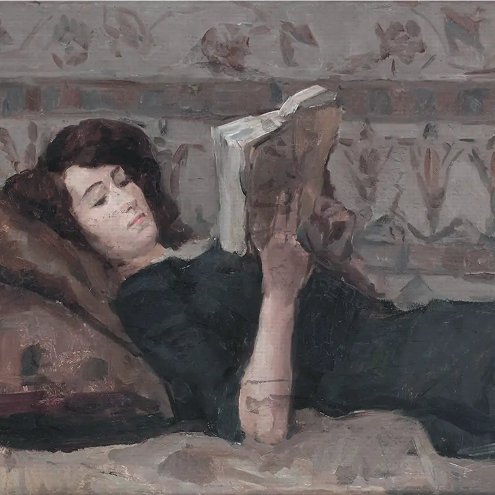A woman in a black dress lies on a couch reading a book, surrounded by patterned upholstery.