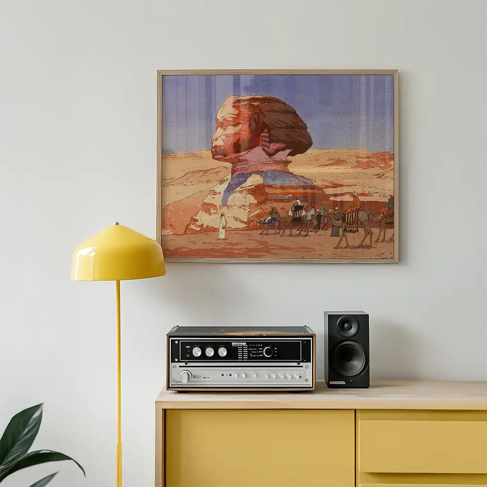 A vibrant wall art painting featuring a desert landscape with a sphinx-like figure and camel caravan, displayed above a retro record player and yellow lamp in a modern interior setting.