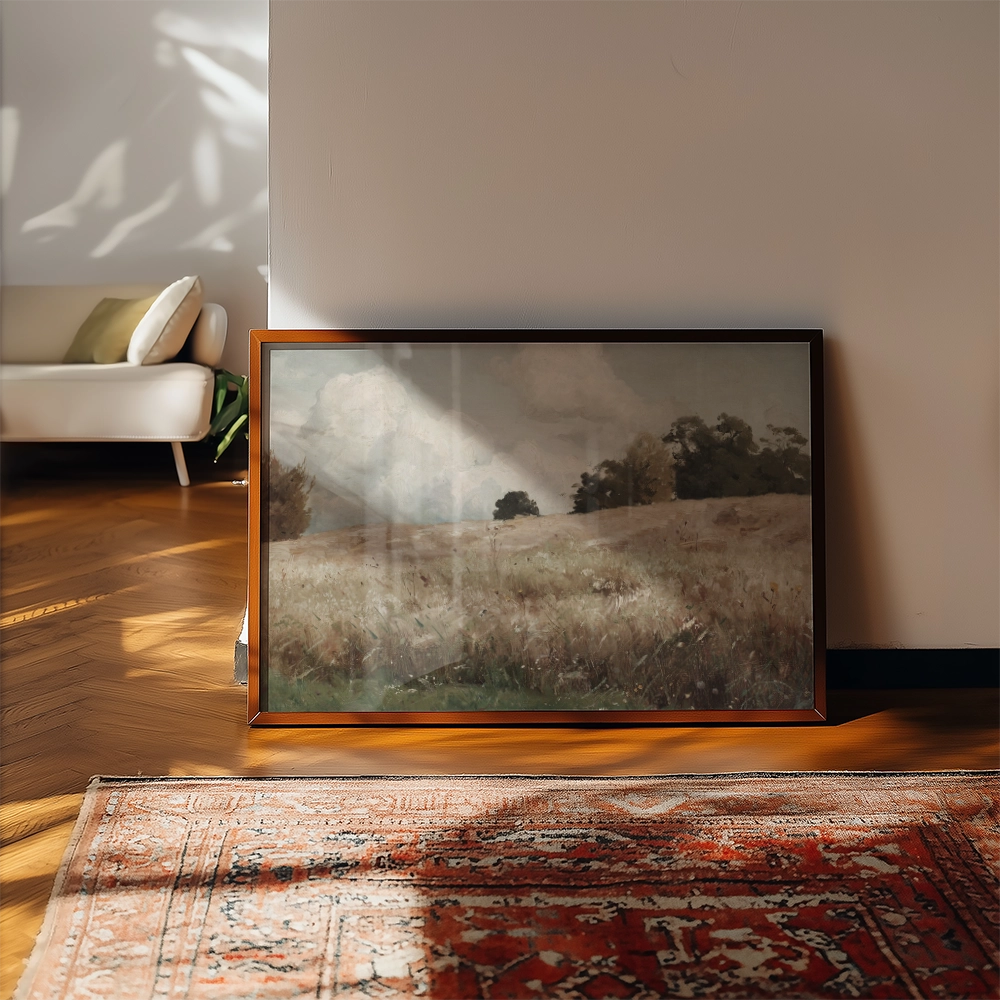Framed landscape painting depicting a serene field with trees under a cloudy sky, placed against a modern interior backdrop.