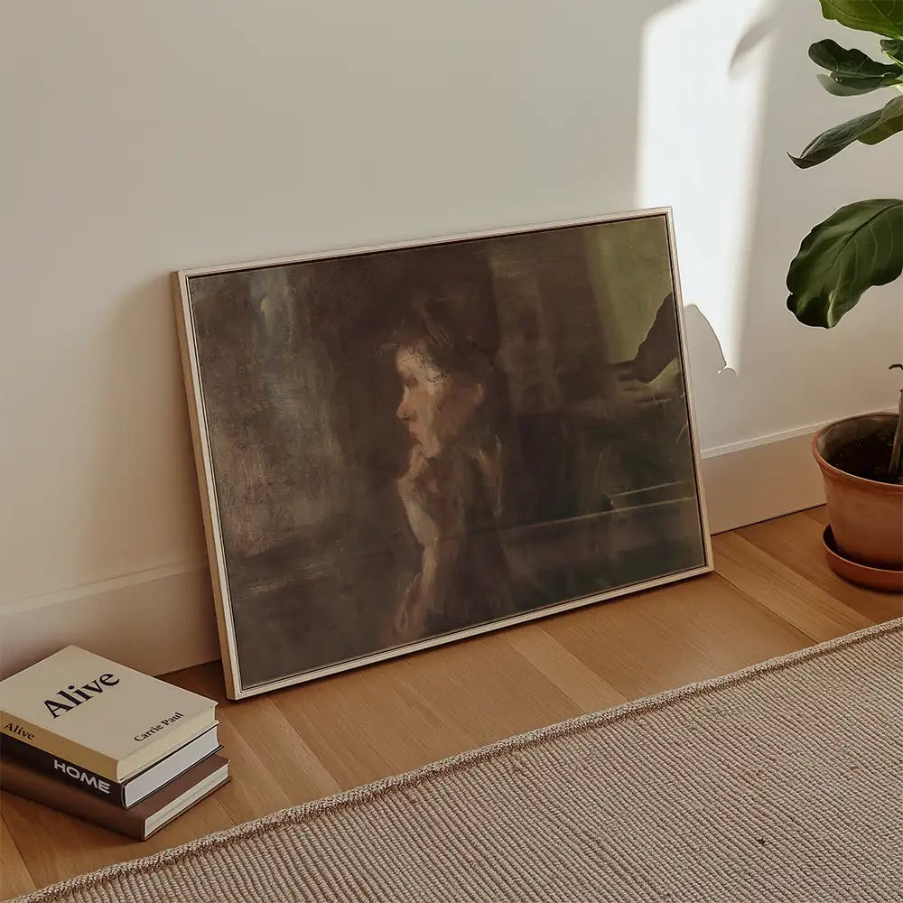 Framed painting of a woman’s profile leaning on her hand, placed on a wooden floor next to stacked books and a potted plant.